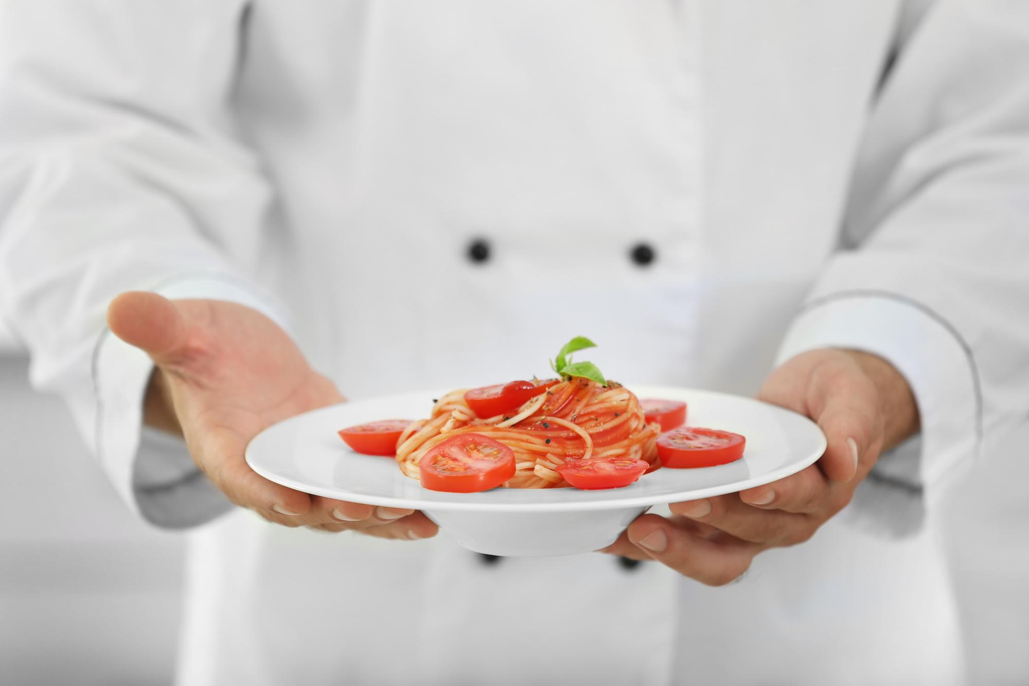 Chef demonstrating precision plating in a modern kitchen